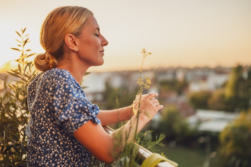 Eine Frau steht mit Kaffeetasse entspannt auf dem Balkon - als Symbol für "Emotionale Überverantwortung lösen"