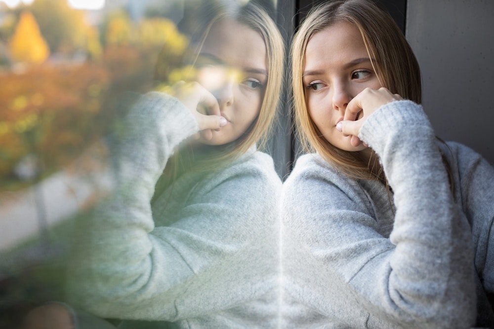 Eine nachdenkliche und etwas unsicher wirkende junge Frau als Symbol für den inneren Kritiker und das Selbstwertgefühl